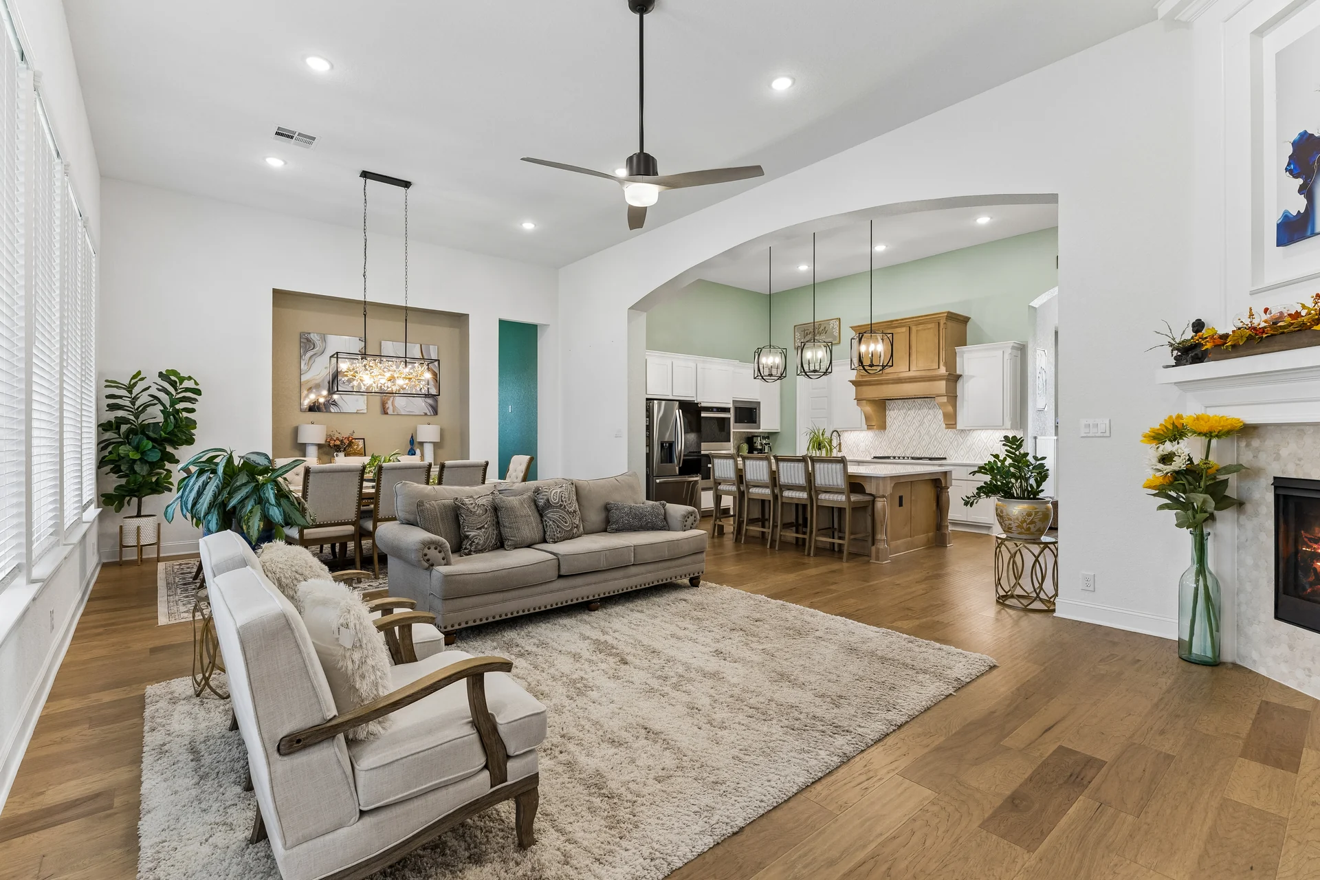 Living room, dining table and island kitchen connected by a broad arch