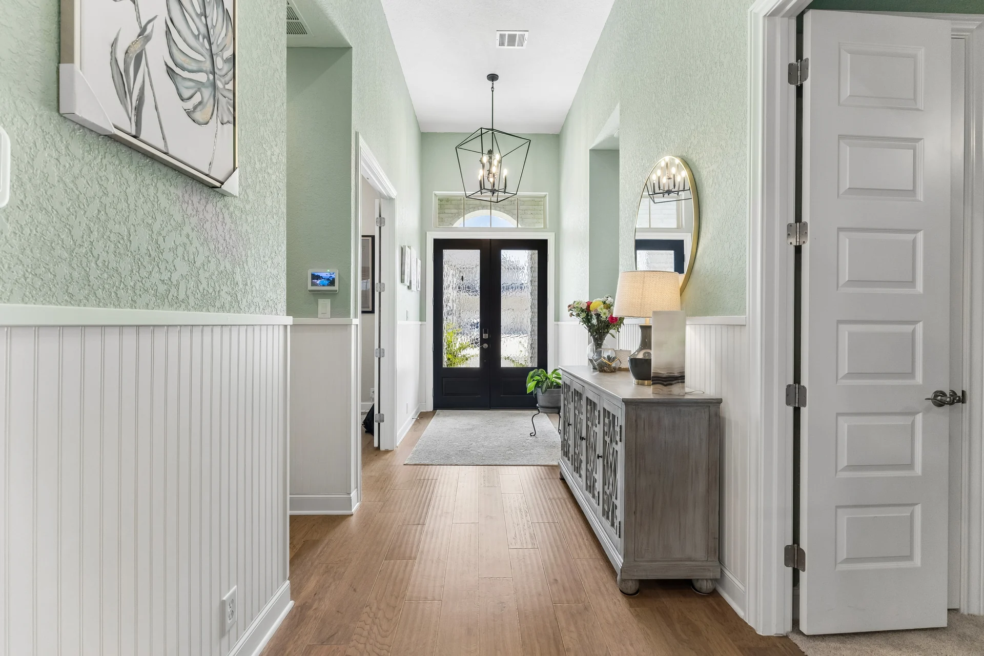 Sage entry hall, white wainscoting and glazed front doors