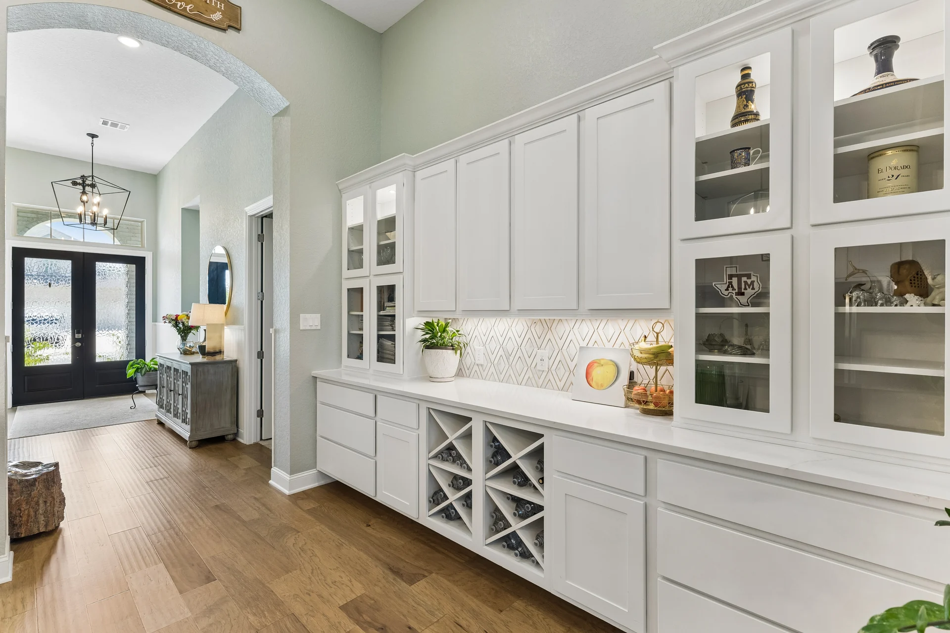 White kitchen cabinetry with display shelves and bottle storage