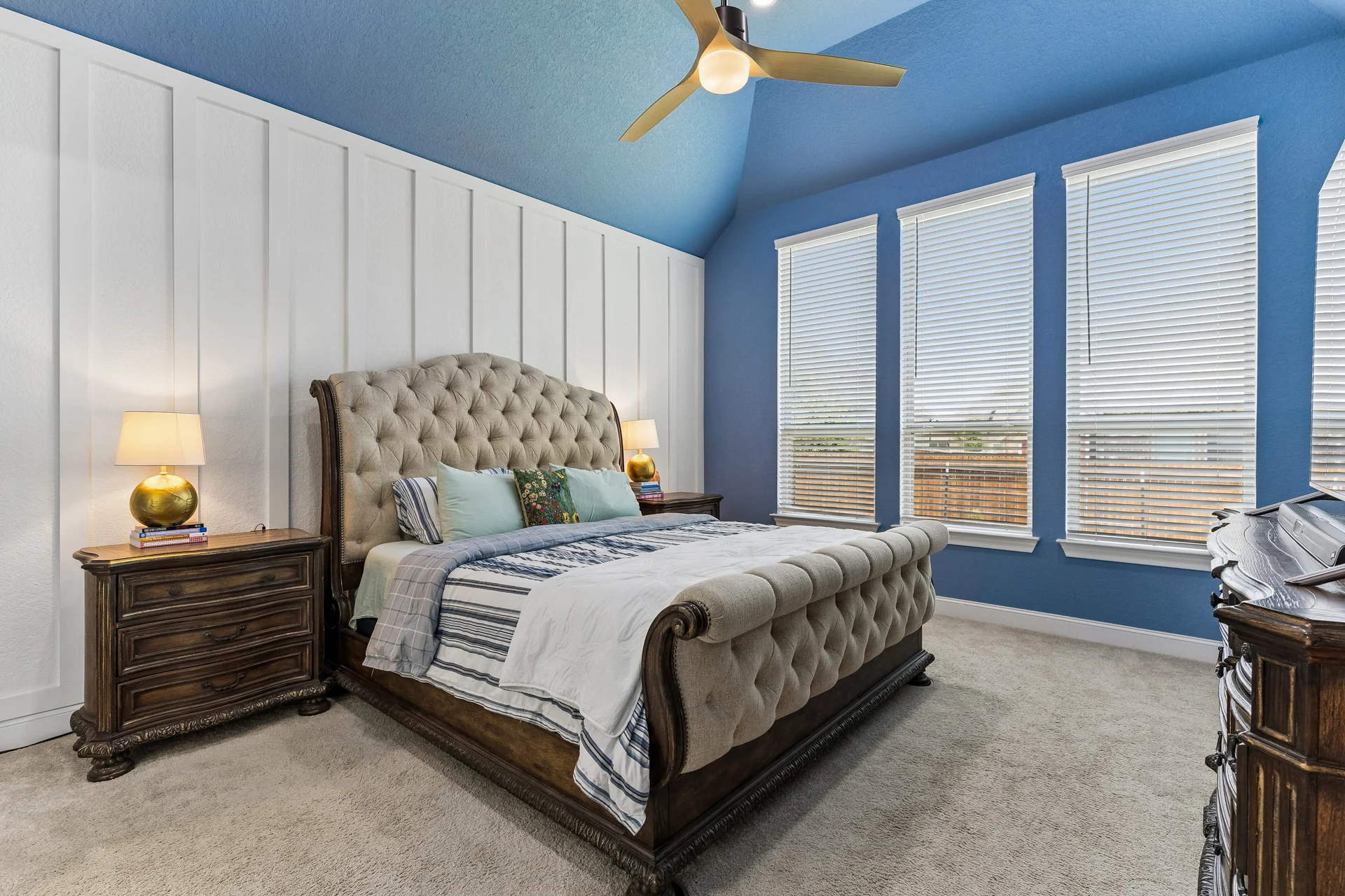 Primary bedroom with blue walls, white paneling and tall windows